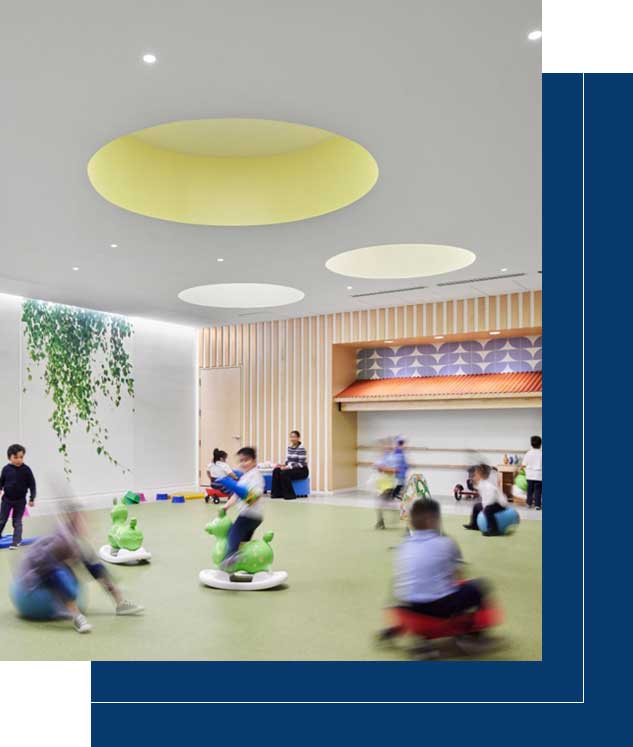 A group of children sitting on the floor in an indoor gym.