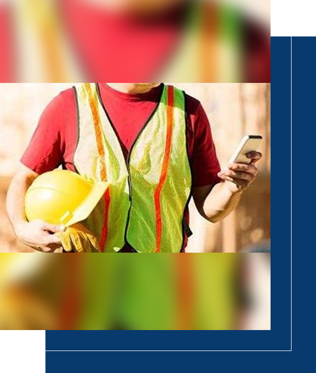 A construction worker holding a hard hat and using his cell phone.