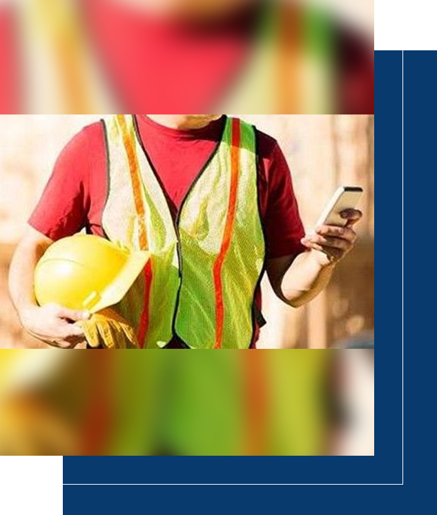 A construction worker holding a hard hat and using his cell phone.