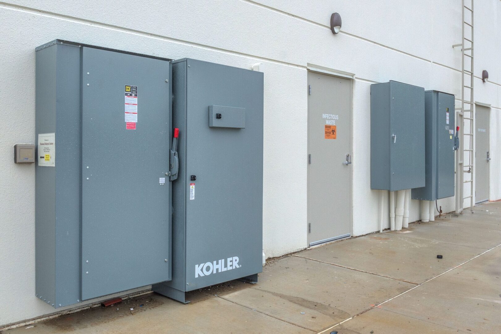 Three electrical boxes are lined up against a wall.