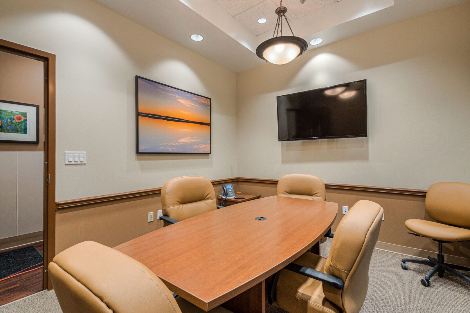 A conference room with a table and chairs, television on the wall.